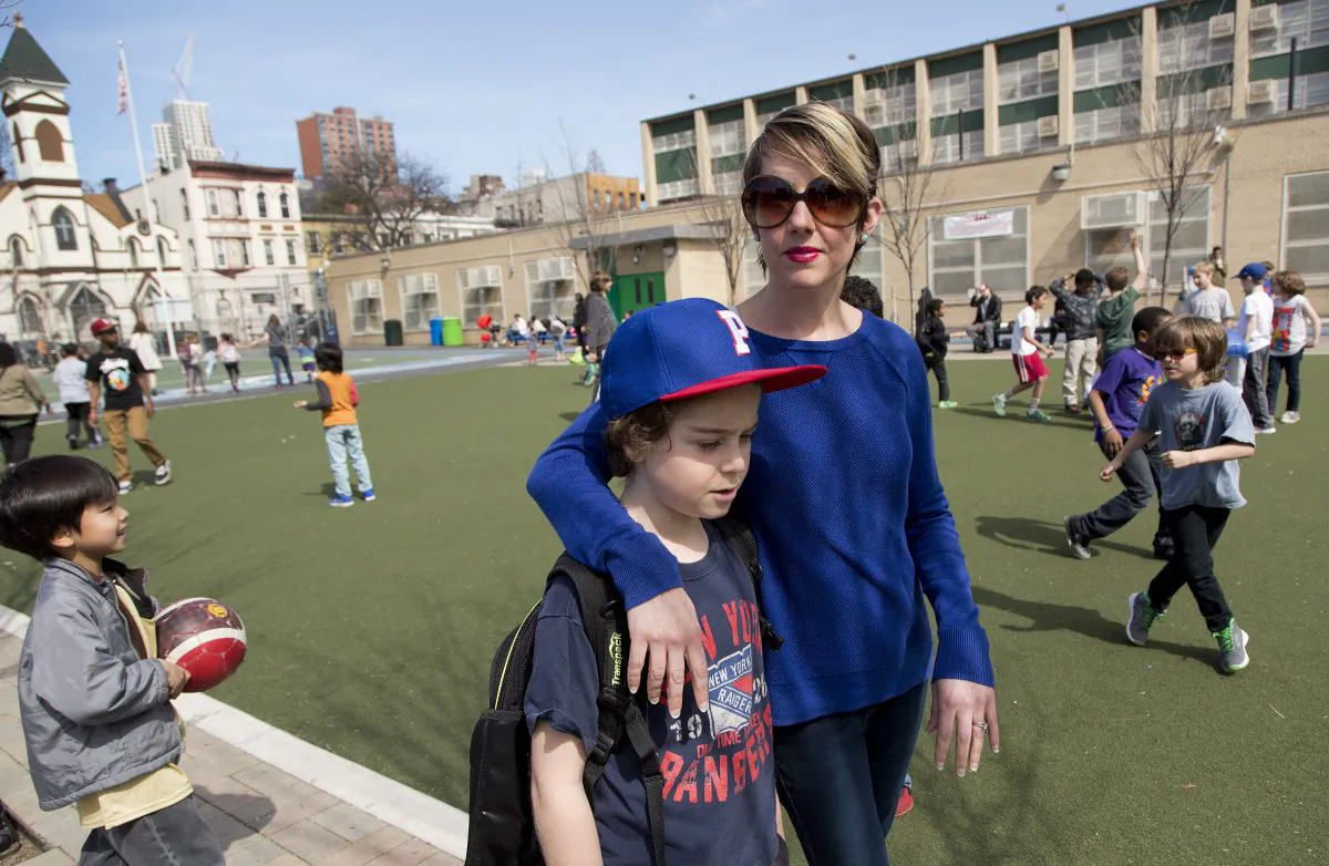 Kristen Couse walks with her son, Wile, on the playground at Public School 261, Thursday, April 16, 2015, in the Brooklyn borough of New York. (AP Photos/Mark Lennihan)