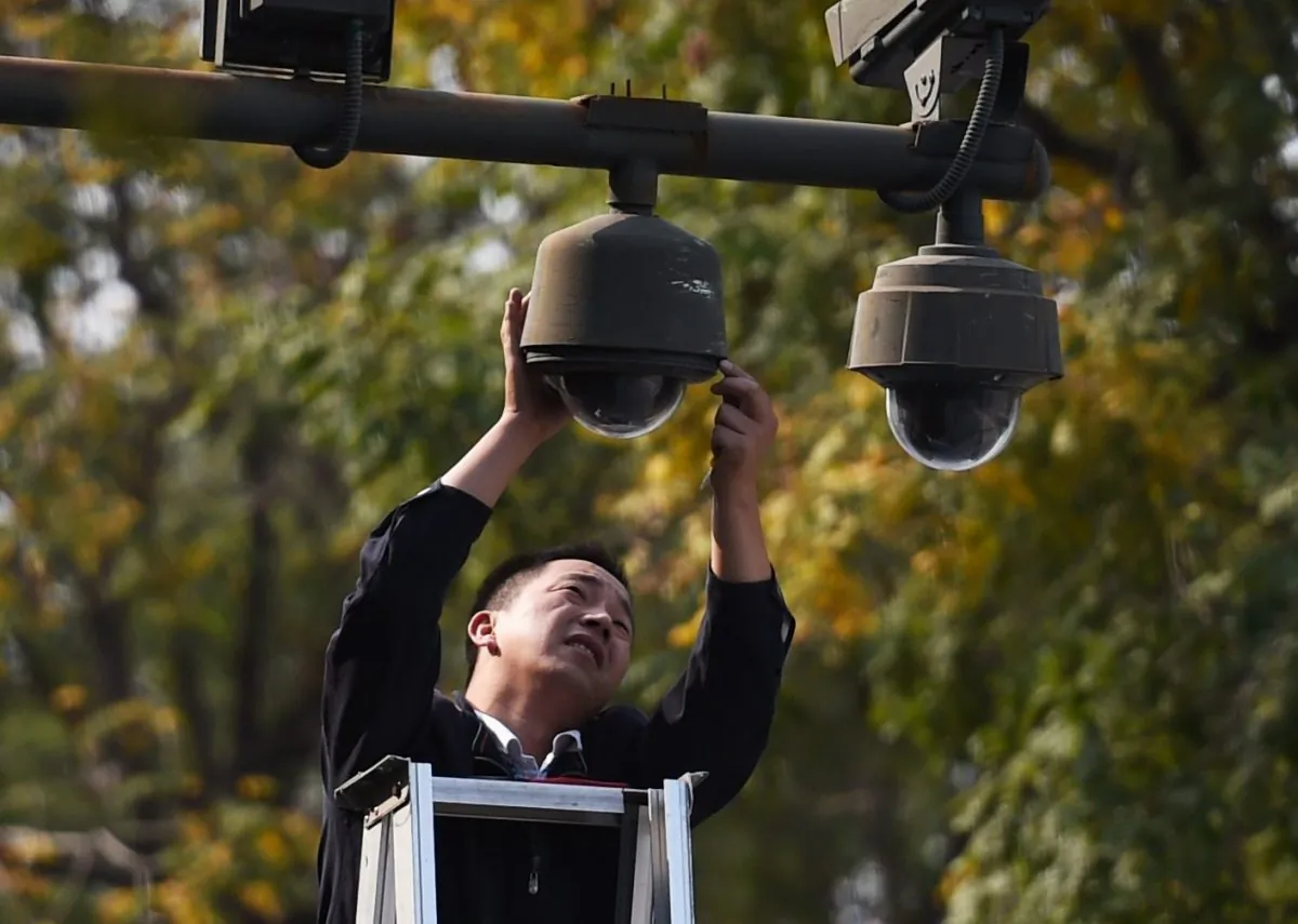 A worker adjusts security cameras on the edge of Tiananmen Square in Beijing on September 30, 2014. (GREG BAKER/AFP/Getty Images)