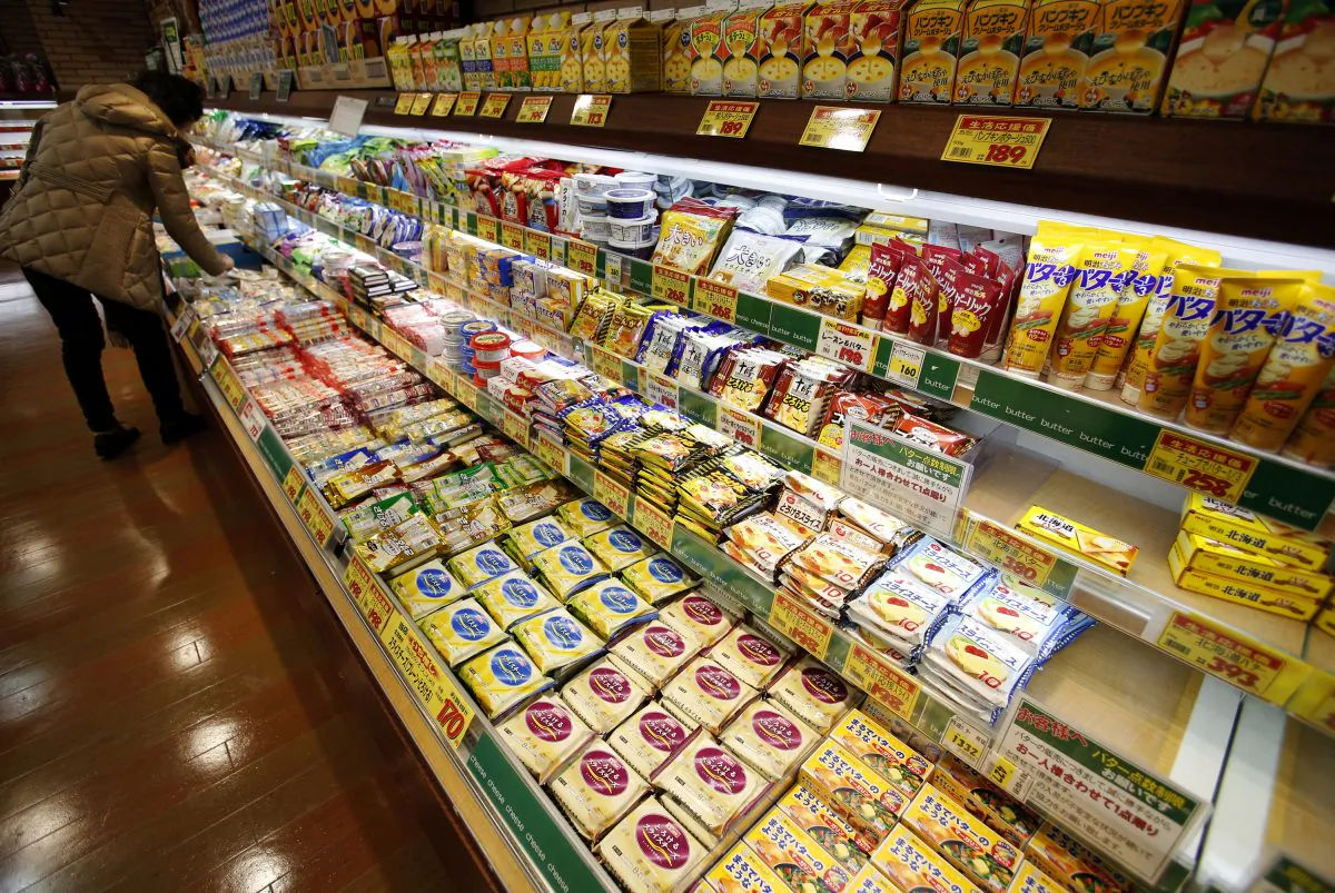 In this Tuesday, Dec. 9, 2014 photo, a shopper chooses dairy products as the shelf selling butter, right, is almost empty at a supermarket in Tokyo. (AP Photo/Shizuo Kambayashi)
