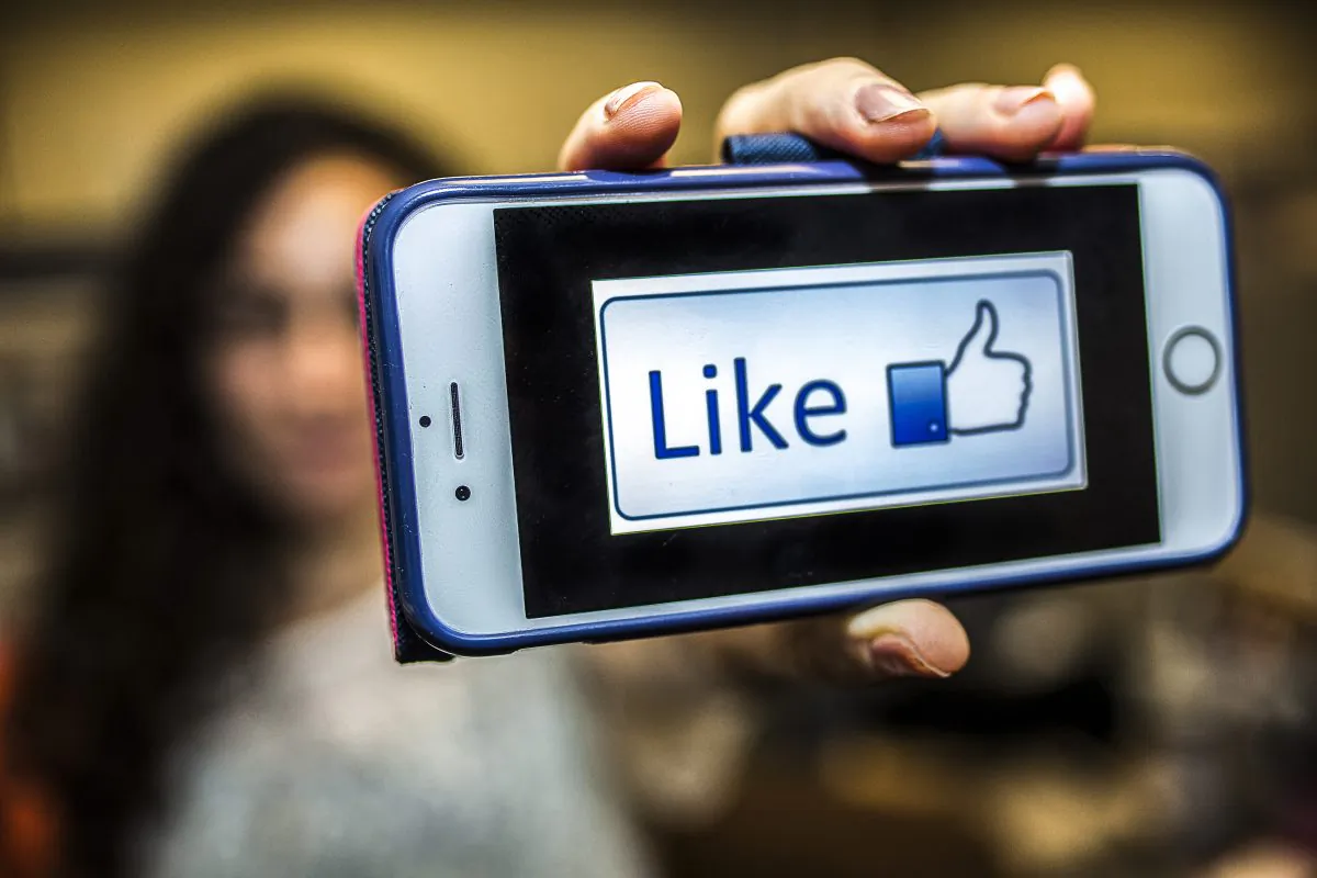 A woman shows a picture of a "like" button on her phone in New York on May 28, 2015. (Petr Svab/Epoch Times)