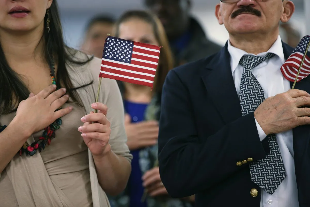 Immigrants hold American flags and listen to the national anthem during a naturalization ceremony (John Moore/Getty Images)