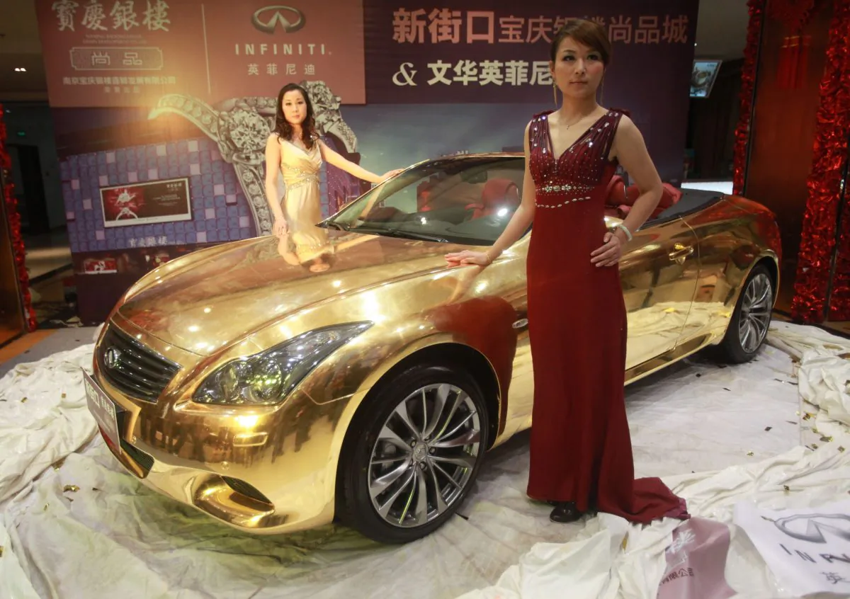 Models pose with a gold-plated Infiniti luxury sports car at a jewellery store in Nanjing, east China's Jiangsu province on March 31, 2011. (STR/AFP/Getty Images)