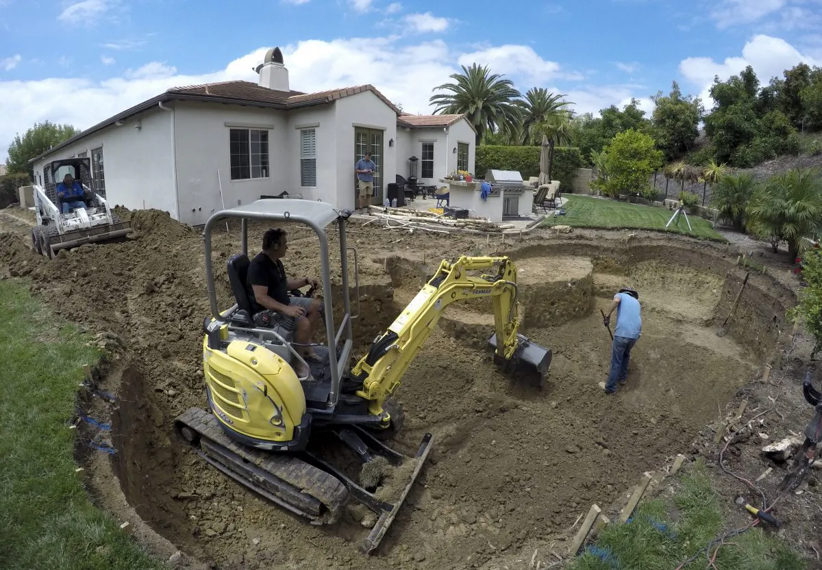 A construction crew digs a new pool behind a house in Tustin, Calif., on May 20, 2015. (AP Photo/Gillian Flaccus)
