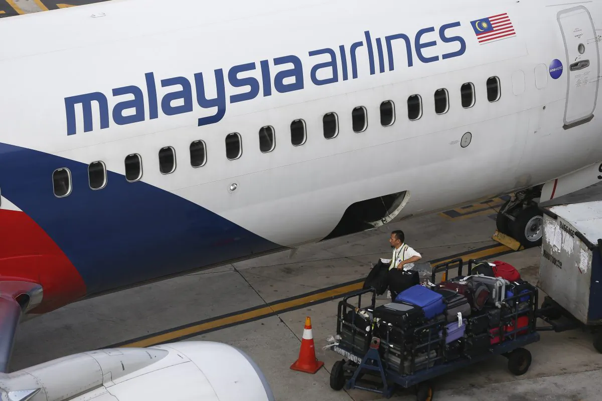 A Malaysia Airlines ground staff member unloads luggage from a plane at Kuala Lumpur International Airport in Sepang, Malaysia Monday, June 1, 2015. (AP Photo/Vincent Thian)