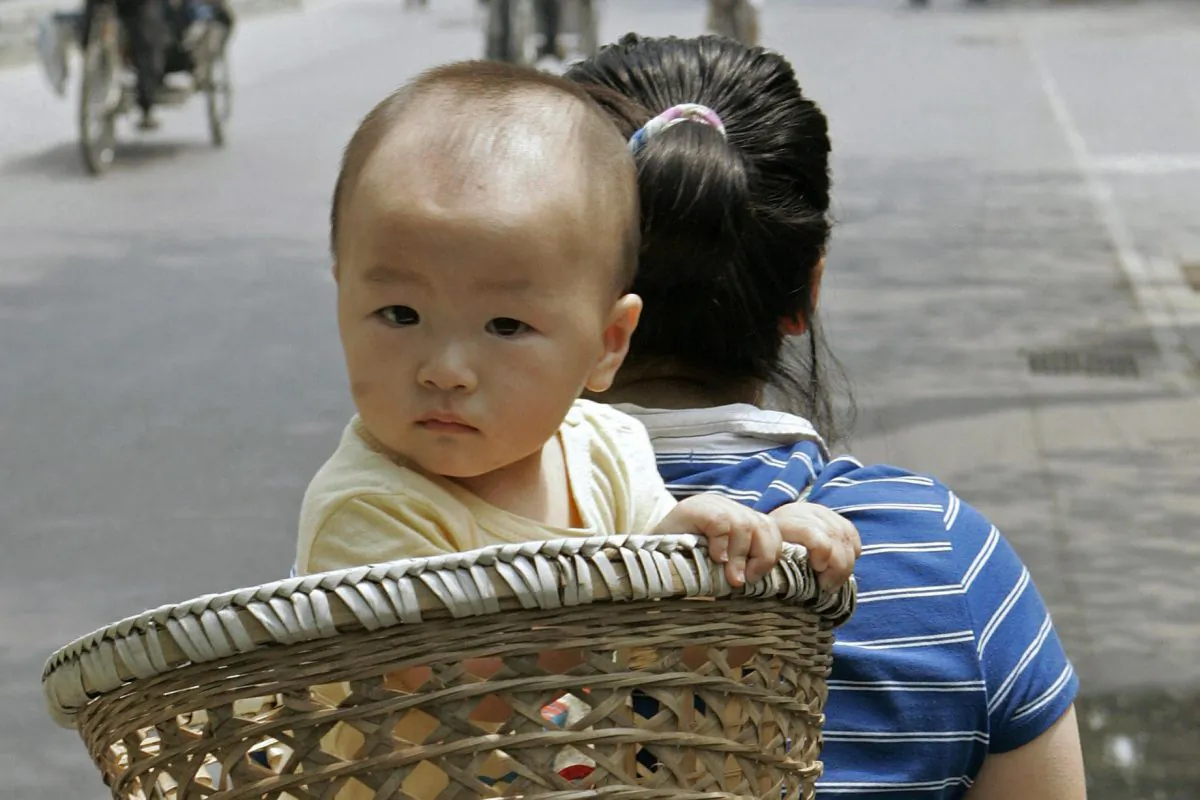 In this file photo, a baby is carried in a basket on his mother’s back on a street in Beijing, June 2007. Cadres in Shandong Province recently found a way to meet their forced abortion quotas and make money. (Peter Parks/AFP/Getty Images)