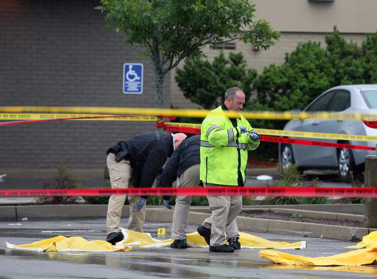 Boston police officers and detectives investigate the scene of a shooting Tuesday, June 2, 2015, in Roslindale, Mass. A man who was under 24-hour surveillance by terrorism investigators was shot and killed after he lunged with a knife at a police officer and an FBI agent outside a pharmacy, authorities said. (Mark Garfinkel/The Boston Herald via AP)