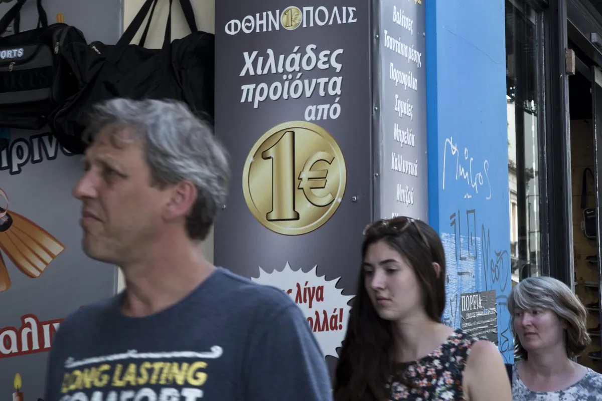 Tourist walks past a discount shop which reads in Greek "thousand of products from one Euro" on Thursday, June 4, 2015. 
(AP Photo/Petros Giannakouris)