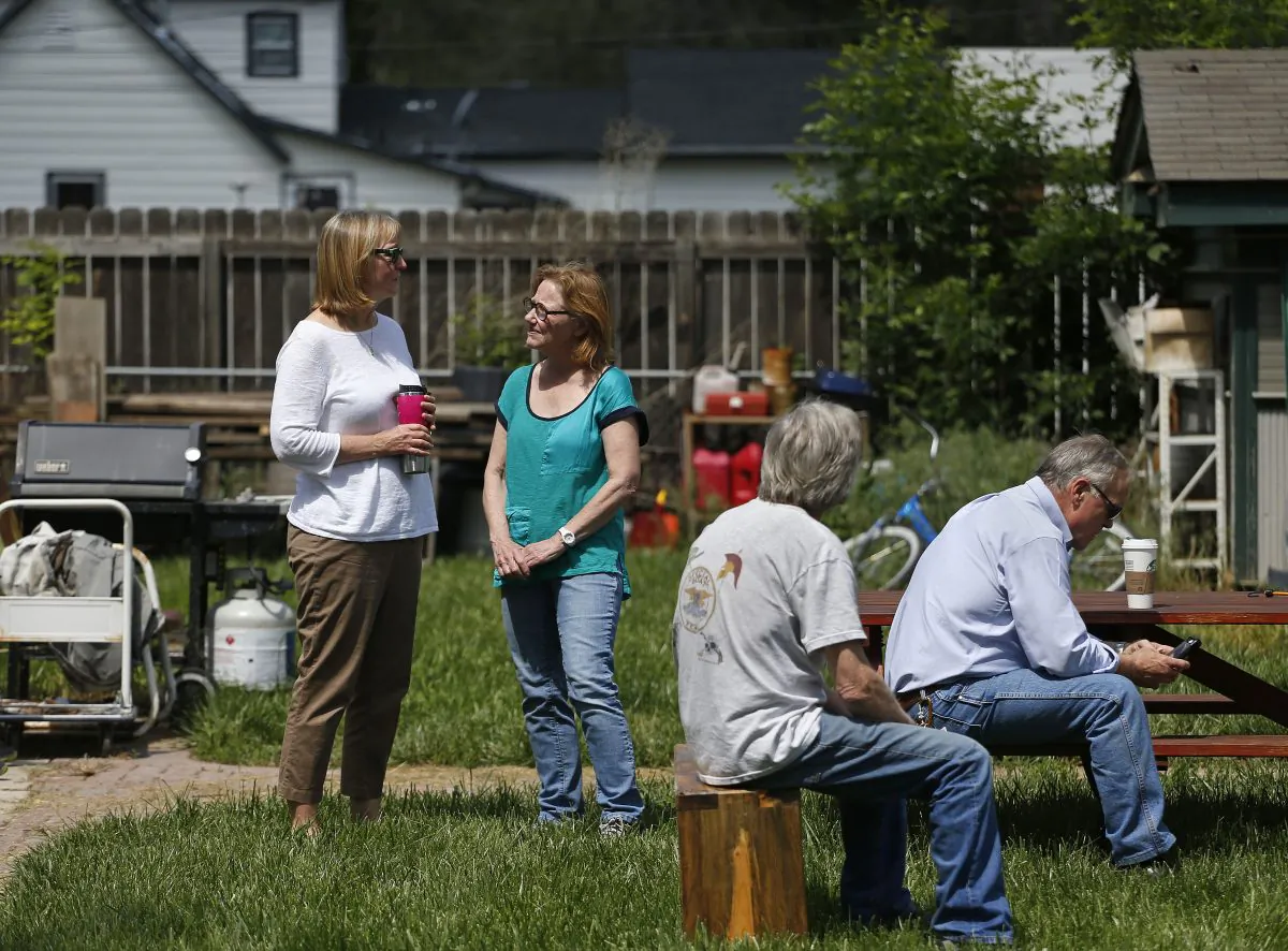 Family members of a slain man, whose name is yet to be officially released, who was shot and killed the night before, stand in the yard of the family home while police performed a search inside, in Loveland, Colo., Thursday, June 4, 2015. (AP Photo/Brennan Linsley)