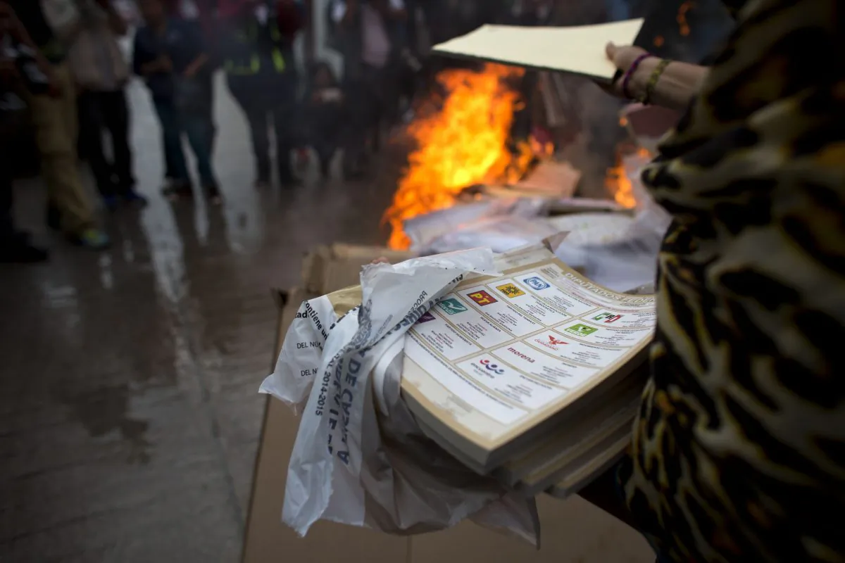 A group of citizens, led by parents of missing students from Ayotzinapa, burn election materials in Tixtla, Guerrero State, Mexico, Sunday, June 7, 2015. The group burned all materials from several polling stations, before meeting resistance from another group of town residents. (AP Photo/Rebecca Blackwell)