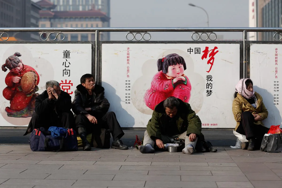 A beggar sits in front of a government propaganda at Beijing Railway Station on March 2, 2014 in Beijing, China. Developed economies are based on a broad middle class—precisely what has not been attained in China. (Lintao Zhang/Getty Images)