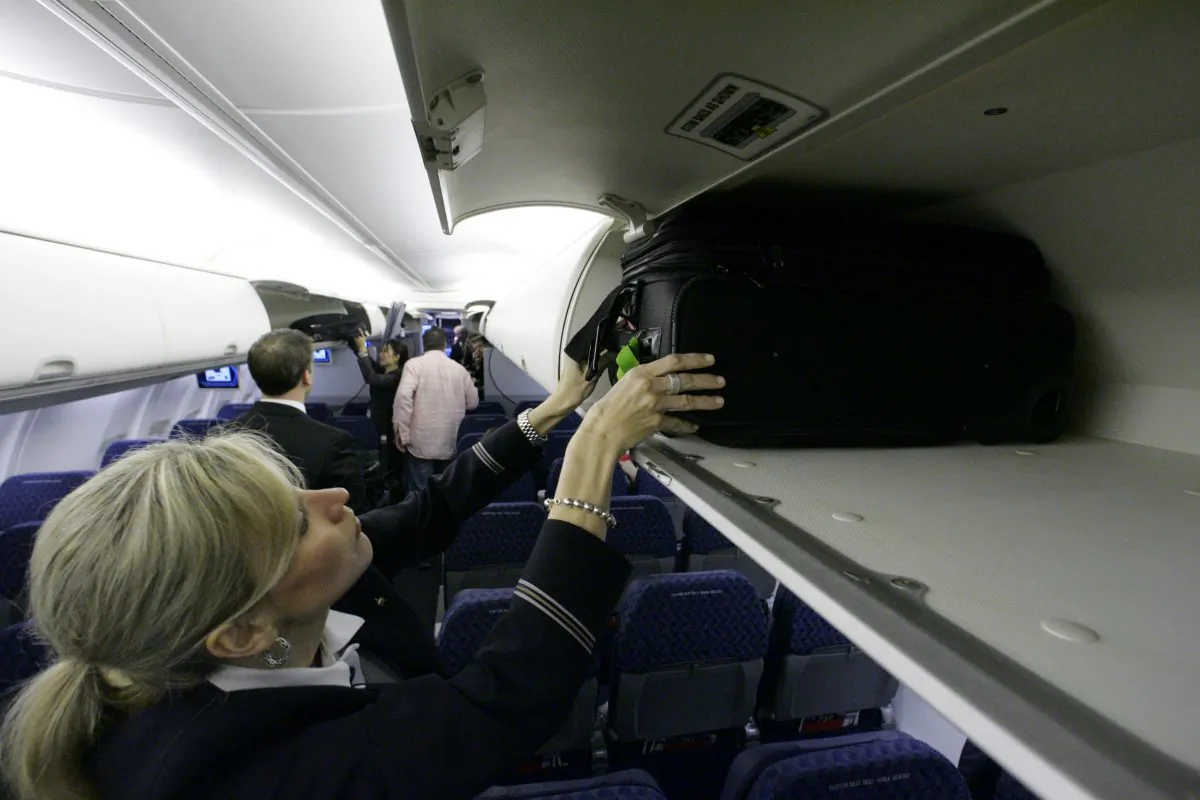 In this April 13, 2009 file photo, American Airlines flight attendant Renee Schexnaildre demonstrates the overhead baggage area. (AP Photo/Donna McWilliam, File)