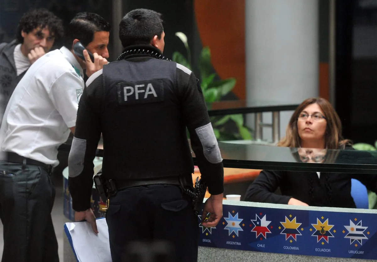 A member of Interpol is seen speaking with staff at the headquarters of Argentine sports broadcaster Torneos y Competencias during a raid in Buenos Aires on May 29, 2015. (STR/AFP/Getty Images)