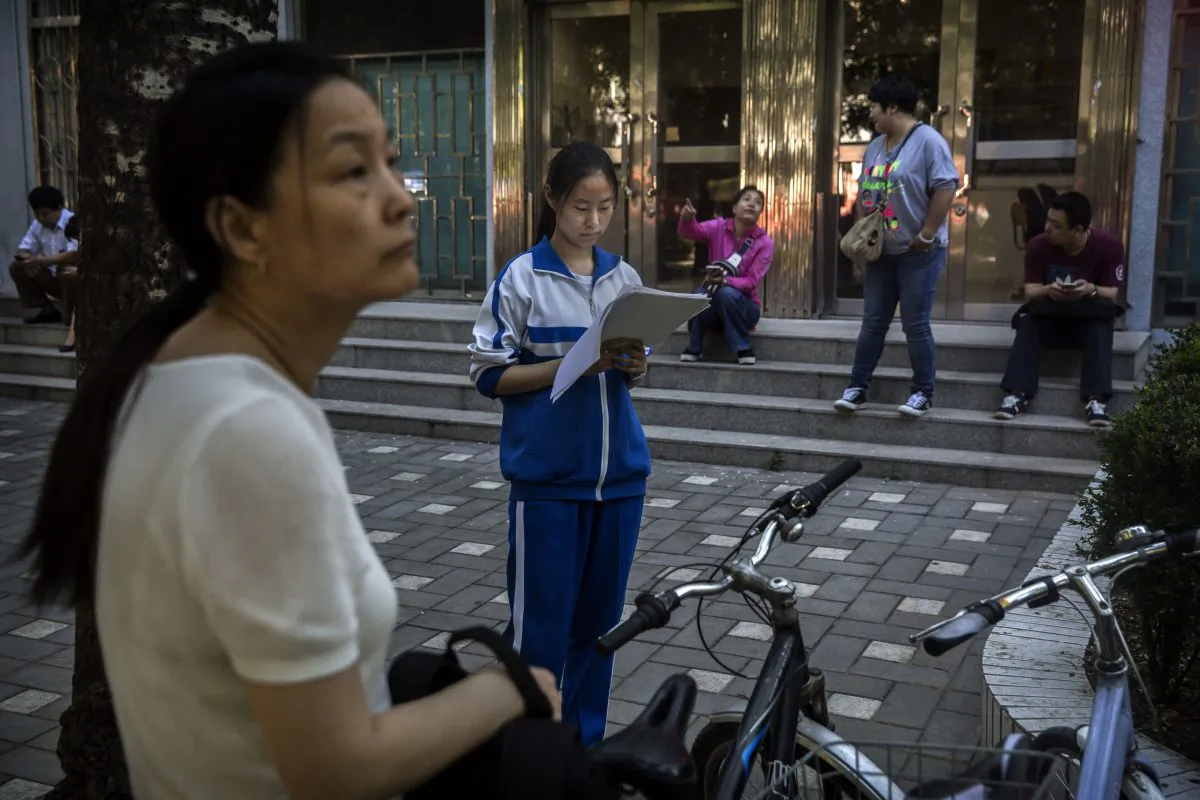 A Chinese student does some last minute studying as her mother looks on outside of the Beijing No. 4 High School, one of the most prestigious in the country, before writing the Gaokao on June 8, 2015 in Beijing, China. (Kevin Frayer/Getty Images
