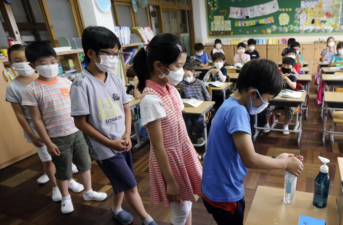 South Korean elementary school students wear masks as a precaution against the MERS, Middle East Respiratory Syndrome, virus as they sanitize their hands to protect against possible MERS virus at an elementary school in Busan, South Korea, Tuesday, June 9, 2015. South Korea is determined to end this week the outbreak of Middle East Respiratory Syndrome, saying upcoming several days will be a critical moment on whether to overcome the medical crisis.(Cha Geun-ho/Yonhap via AP)