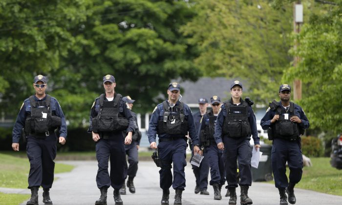 Law enforcement officers walk the streets in Dannemora, N.Y., as they searched houses near the maximum-security prison in northern New York where two killers escaped using power tools,Wednesday, June 10, 2015.  State Police said the fifth day of searching will entail going from house to house in Dannemora, where David Sweat and Richard Matt cut their way out of the Clinton Correctional Facility.  (AP Photo/Seth Wenig)