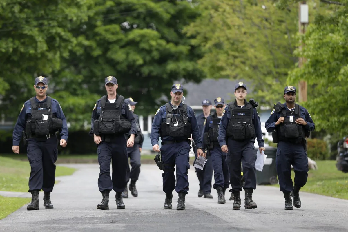 Law enforcement officers walk the streets in Dannemora, N.Y., as they searched houses near the maximum-security prison in northern New York where two killers escaped using power tools, Wednesday, June 10, 2015. (AP Photo/Seth Wenig)