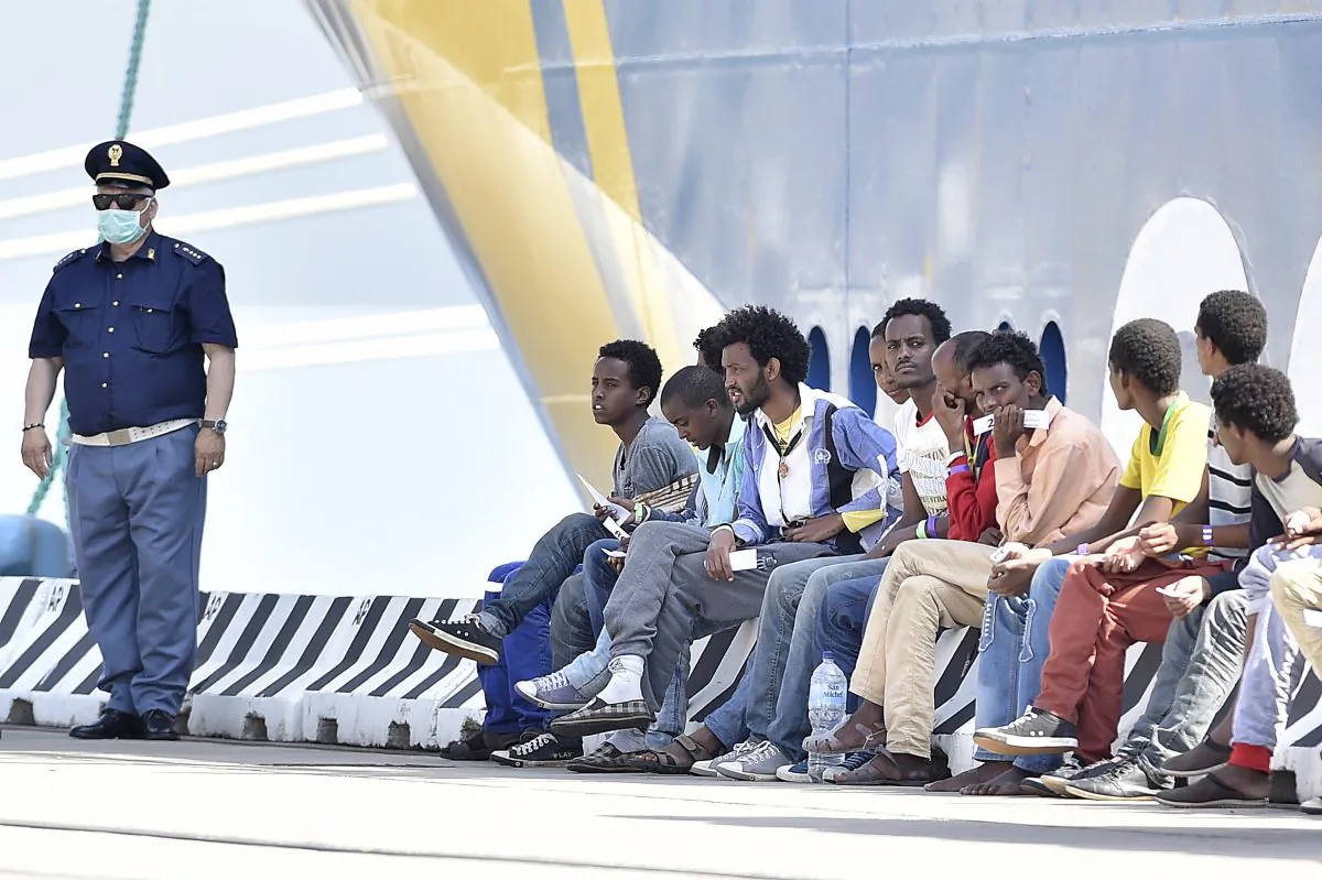 An Italian police officer stands next rescued migrants after they disembarked from the Swedish Coast Guard ship KBV 001 Poseidon at Messina harbor Italy, Tuesday, June 9, 2015. (AP/Carmelo Imbesi)