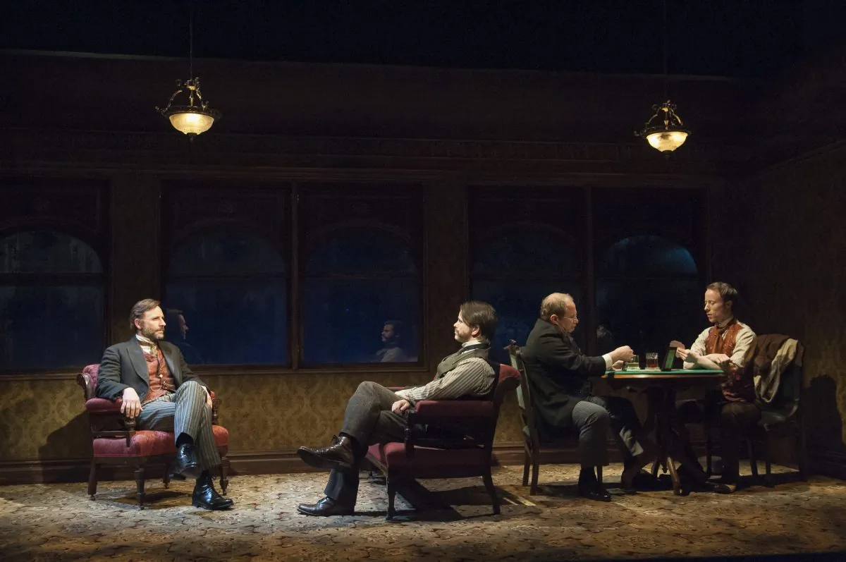(L–R) Storyteller (Jordan Lage) relates a brush he had with the supernatural years earlier to a companion (Jason Ritter) while a card player (Jim Frangione) eavesdrops, disturbing his game with the dealer (Nate Dendy). (Ahron Foster)