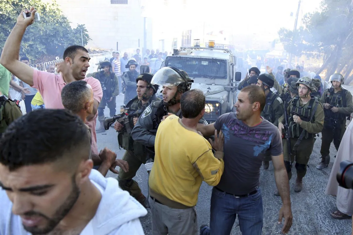 Palestinian scuffle with Israeli soldiers after a Palestinian was killed in clashes with Israeli forces in the village Kafr Malik near the West Bank city of Ramallah, Sunday, June 14, 2015. (AP Photo/Majdi Mohammed)