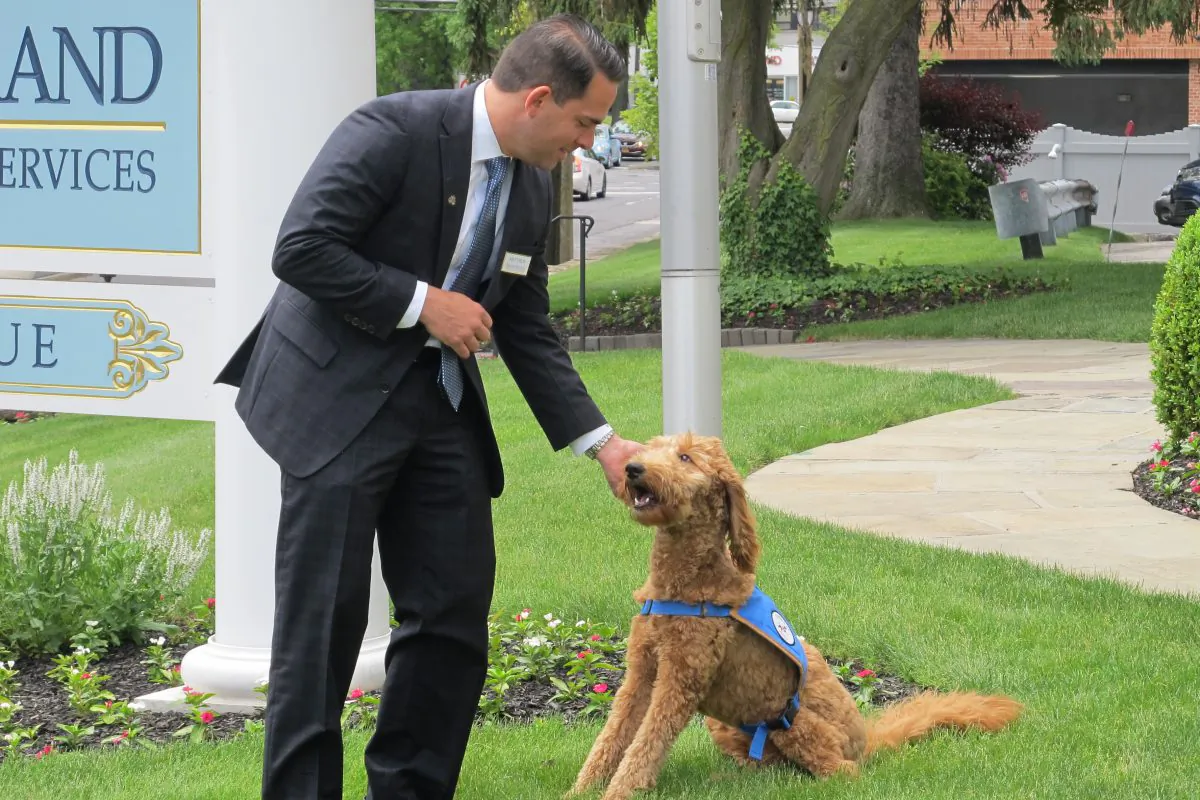 Matthew Fiorillo, owner of the Ballard-Durand funeral home in White Plains, N.Y., plays with his dog Lulu on the funeral home's lawn on Thursday, June 4, 2015. (AP Photo/Jim Fitzgerald)