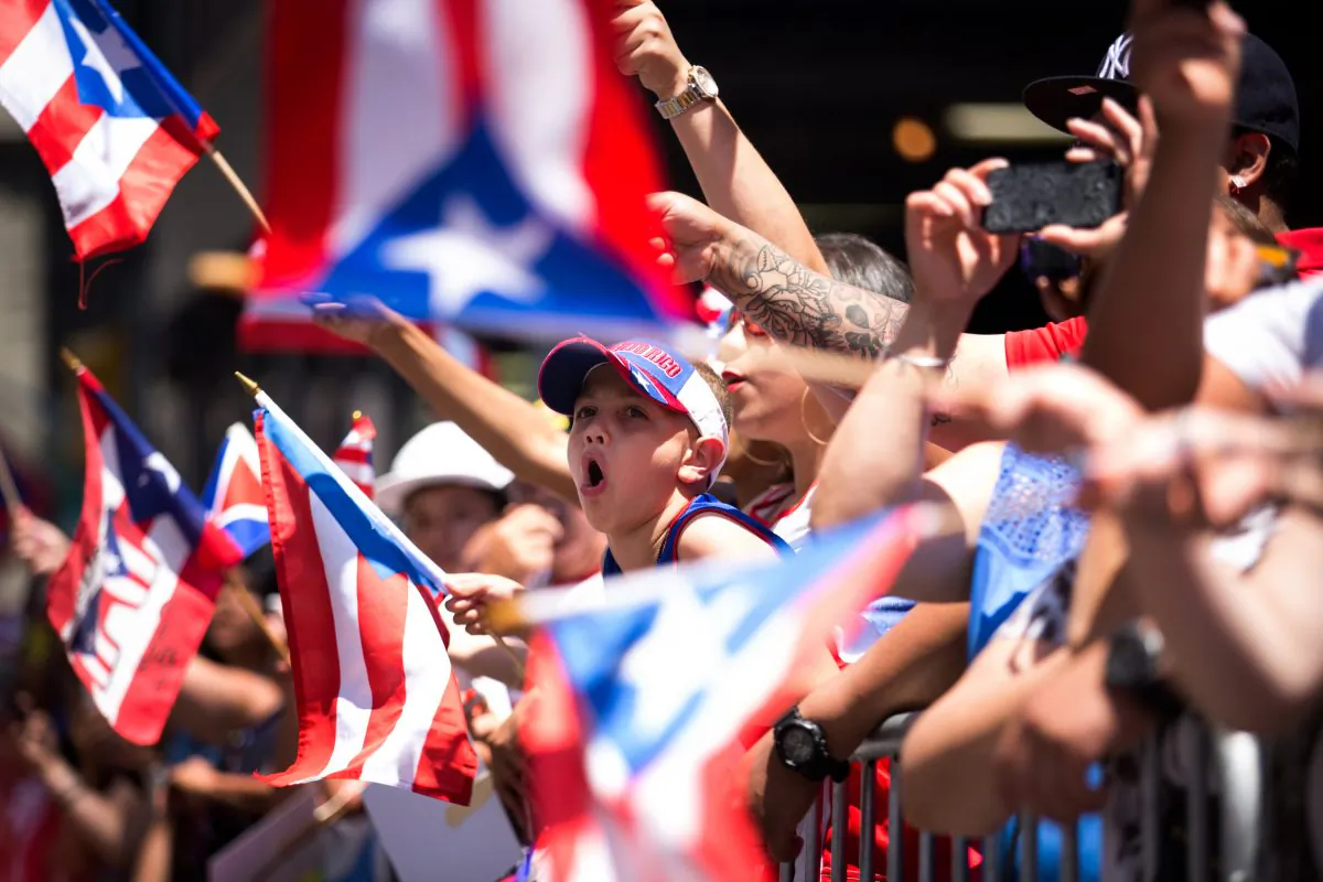 Jaydden Garcia (C), 8, cheers as the annual National Puerto Rican Day Parade makes its way up New York's Fifth Ave., Sunday, June 14, 2015.  (AP Photo/Kevin Hagen)