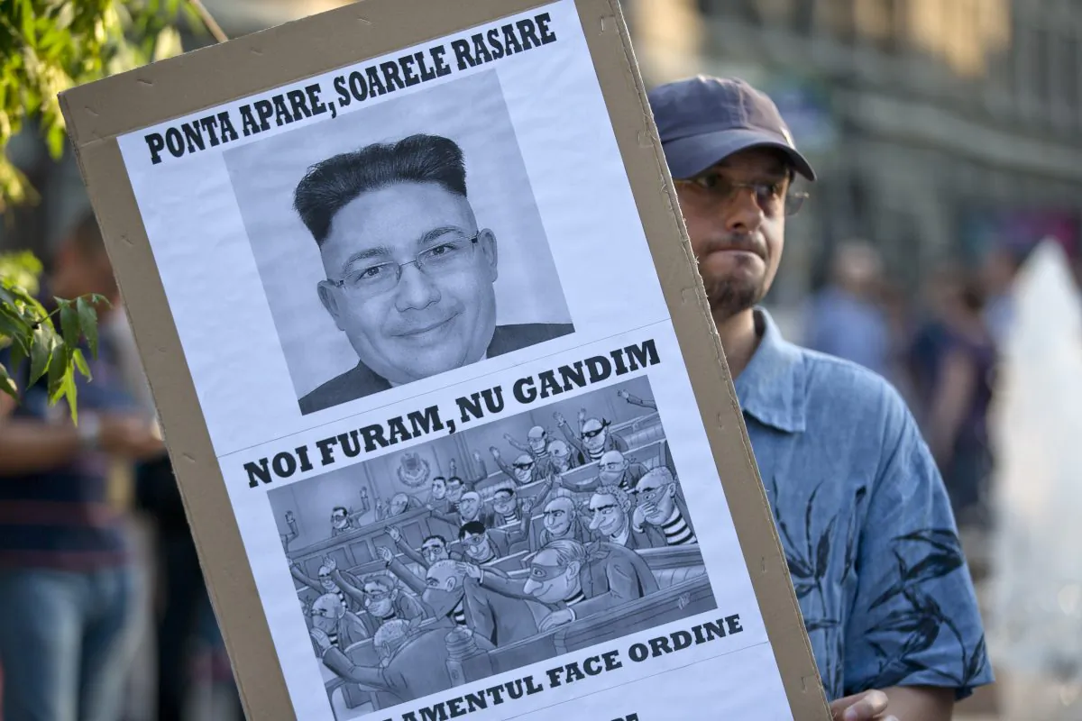 A man holds a banner depicting Romania's Premier Victor Ponta as North Korean leader Kim Jong-un, during a protest demanding his resignation in Bucharest, Romania, Thursday, June 11, 2015. (AP Photo/Vadim Ghirda)