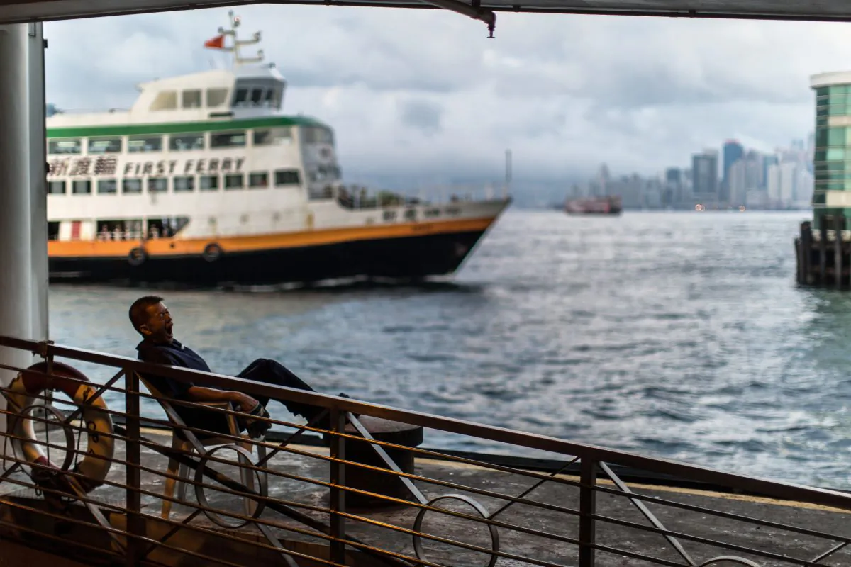 A ferry worker yawns as he waits for a commuter ferry to dock in Hong Kong on May 1. The Chinese regime's People's Liberation Army is commissioning the construction of ferries as troops transports. (Anthony Wallace/AFP/Getty Images)
