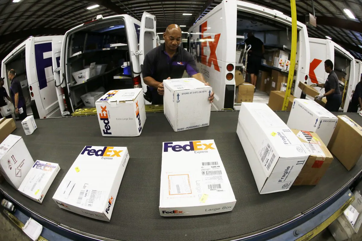 Workers load packages into delivery trucks at the FedEx Express station in Nashville, Tenn. (AP Photo/Mark Humphrey)