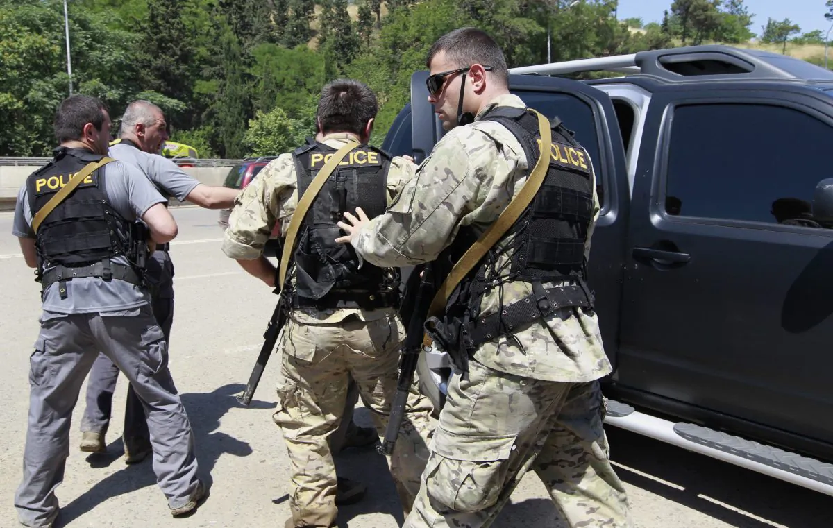 Georgian police commandos get into a car after a tiger that broke loose after flooding at a Zoo, was shot by police in Tbilisi, Georgia, Wednesday, June 17, 2015. (AP Photo/Shakh Aivazov)