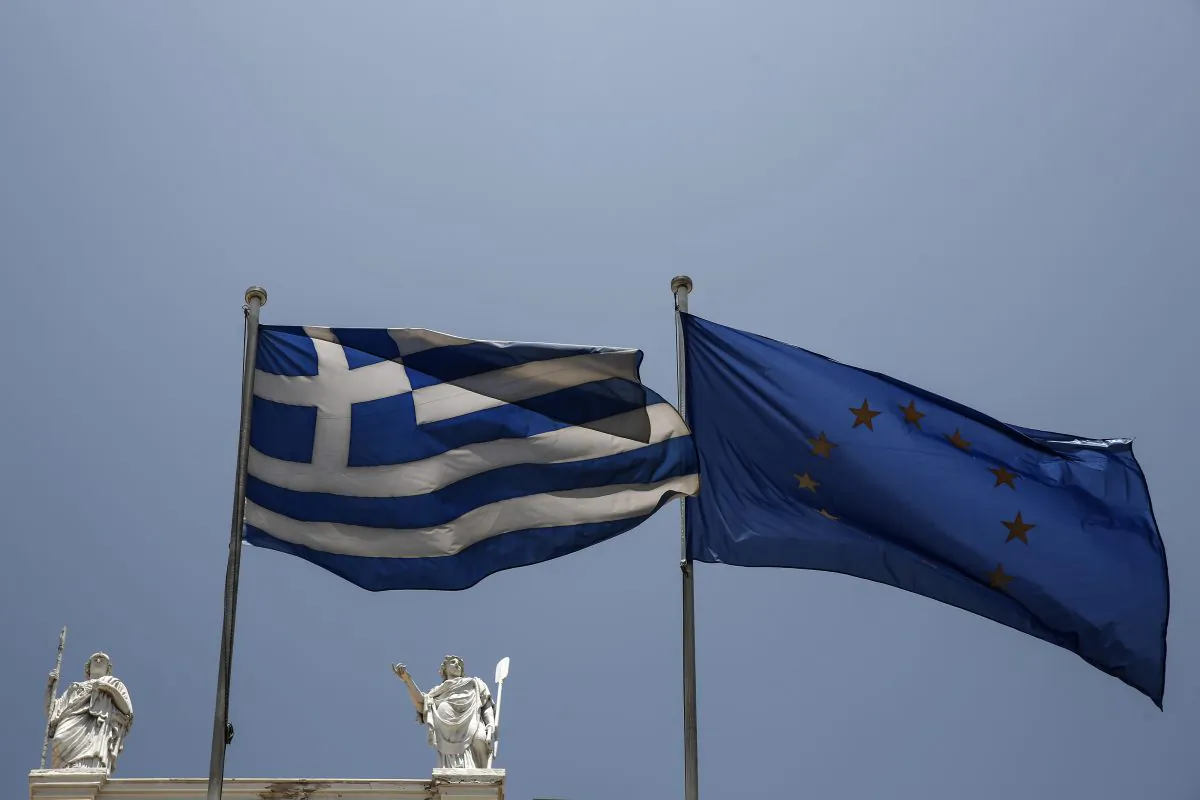 A Greek and a European Union flags flutter in front of statues of goddess Athena, left, and Nautilia, in front of Benaki museum in Athens, Greece, on Wednesday, June 17, 2015.  (AP Photo/Yorgos Karahalis)