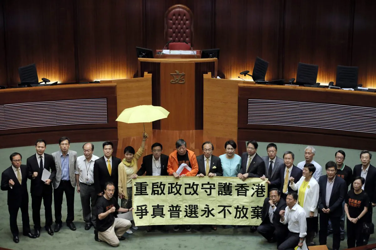 Pro-democracy lawmakers display a yellow umbrella and a banner stating "Reopen political reform to protect Hong Kong, never give up to fight for true universal suffrage" after 28 lawmakers voted against the election reforms proposals at the Legislative Council in Hong Kong, June 18, 2015. (AP Photo/Vincent Yu)