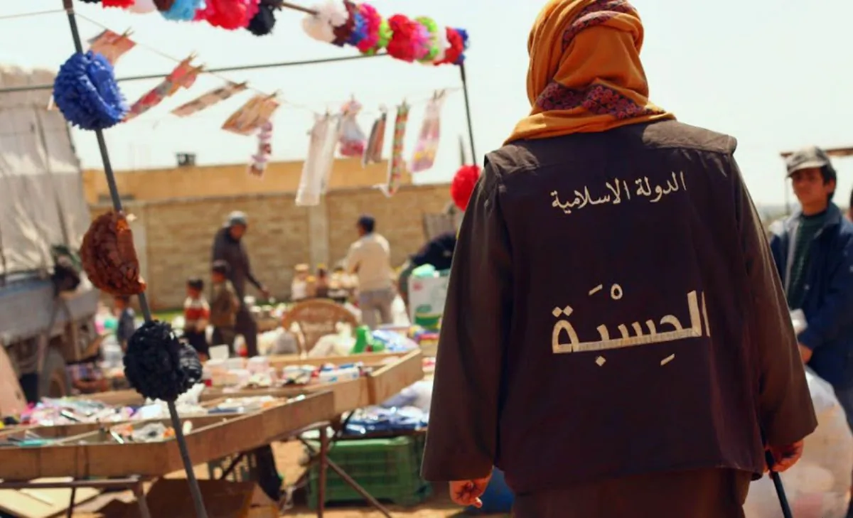In this photo released on April 17, 2015 by a militant website, which has been verified and is consistent with other AP reporting, a member of the Islamic State group's vice police known as "Hisba," patrols a market in Raqqa City, Syria. The Arabic words on the vest read, "The Islamic State - Hisba (vice police)." (Militant website via AP)