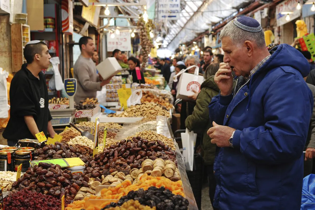A man shopping for fresh fruits, is tasting a fresh fig in a market stall at the famous Mahane Yehuda Market in dowtown Jerusalem. (MaestroBooks, iStock)