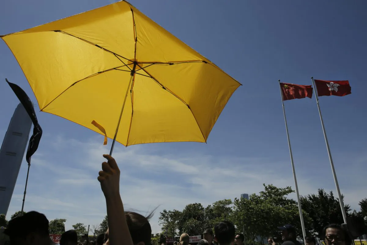 A pro-democracy protester raises a yellow umbrella in front of a Chinese national flag and a Hong Kong flag after lawmakers voted against the election reform proposals in Hong Kong, June 18, 2015. (AP Photo/Vincent Yu)