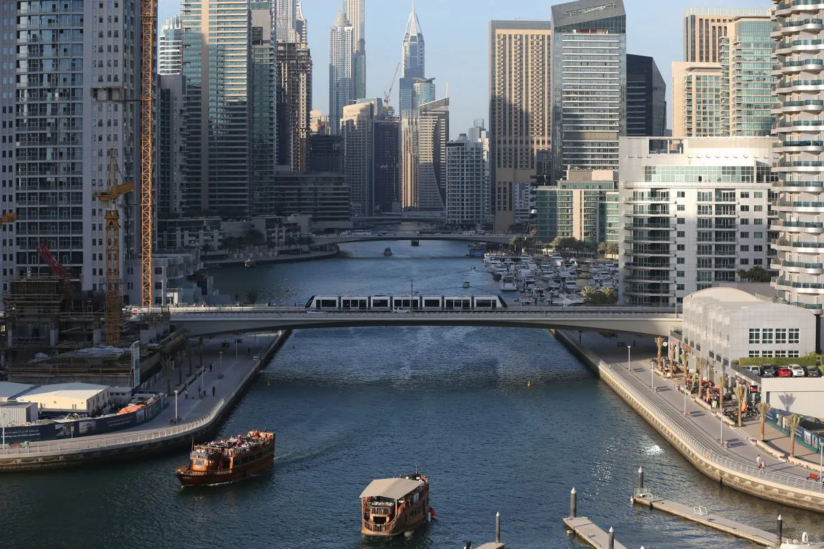 In this April 1, 2015 photo, tourists and visitors enjoy their dhow cruise trips at the Marina water canal as a tram crosses on a bridge in Dubai, United Arab Emirates. (AP Photo/Kamran Jebreili)