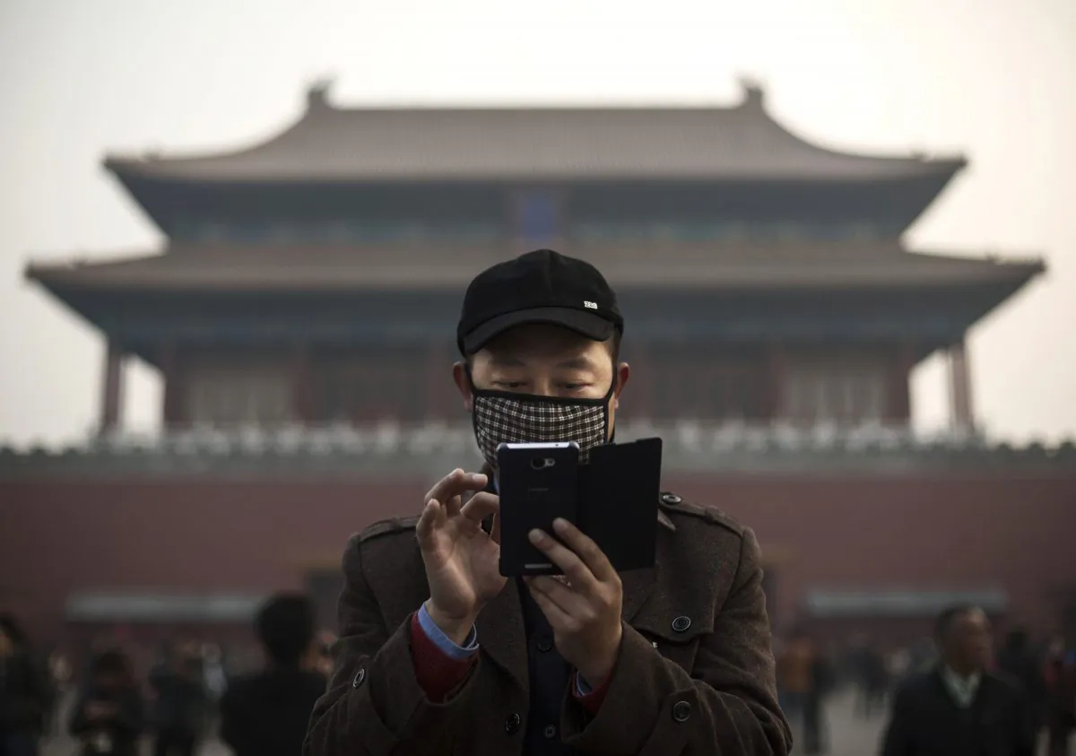 A Chinese man uses his smartphone outside the Forbidden City in Beijing on Nov. 20, 2014. (Kevin Frayer/Getty Images)
