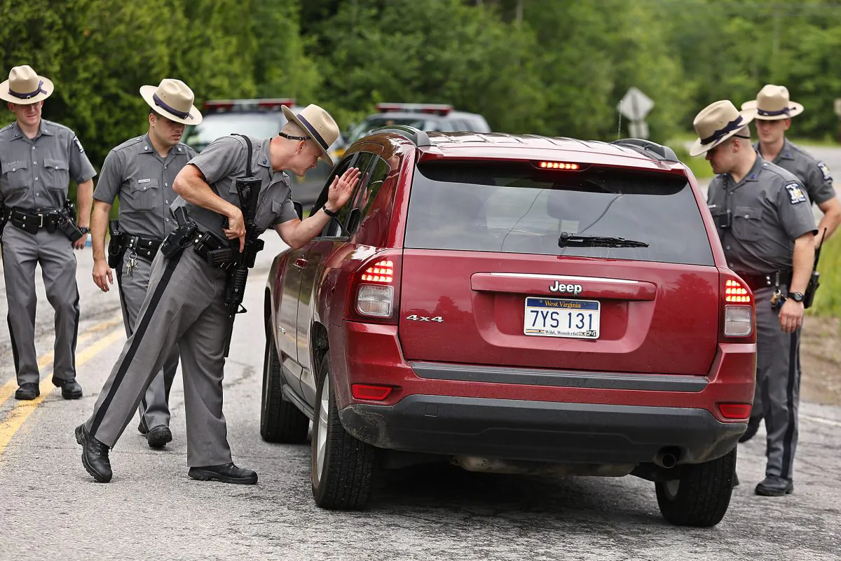 New York State Trooper Steven J. Gill searches a vehicle in Malone, N.Y., Tuesday, June 23, 2015, while searching for two prison escapees from Clinton Correctional Facility. Police began focusing intensely on an area 20 miles west of the prison that inmates David Sweat and Richard Matt escaped from prison on June 6. (Jason Hunter/The Watertown Daily Times via AP) 