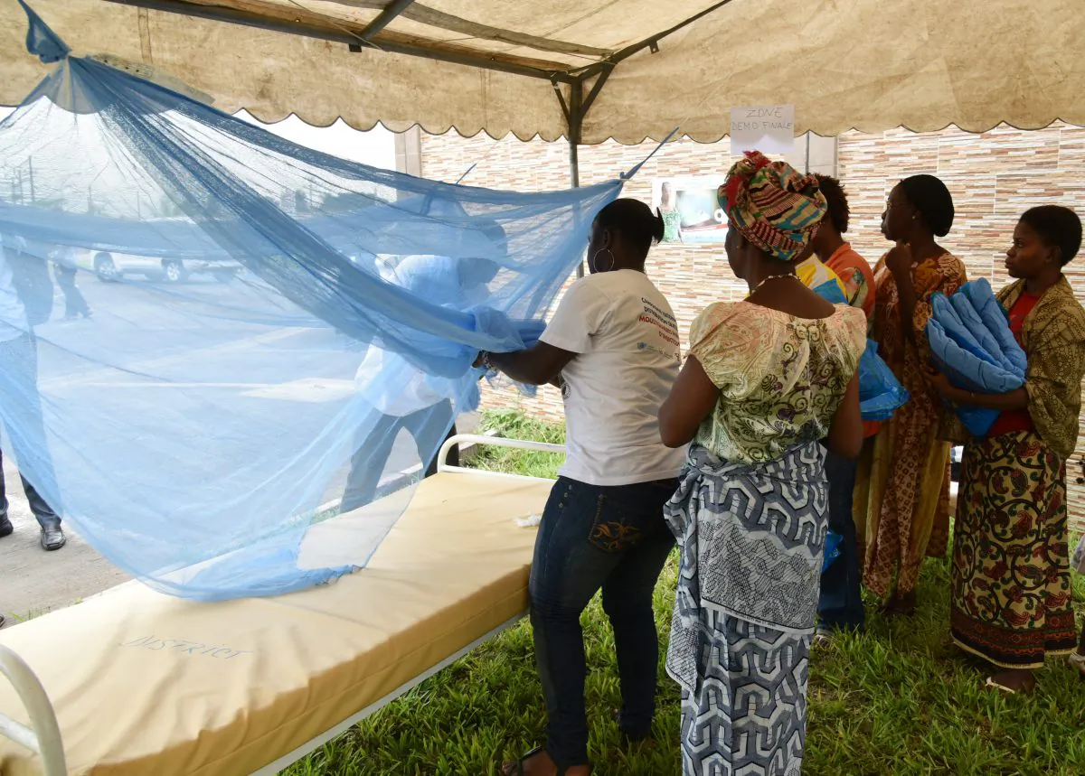 People show how to put a mosquito net on a bed during a free insecticide-treated mosquito nets distribution on April 24, 2015 at the town hall in the Port-Bouet popular district of Abidjan. (Sia Kambou/AFP/Getty Images)