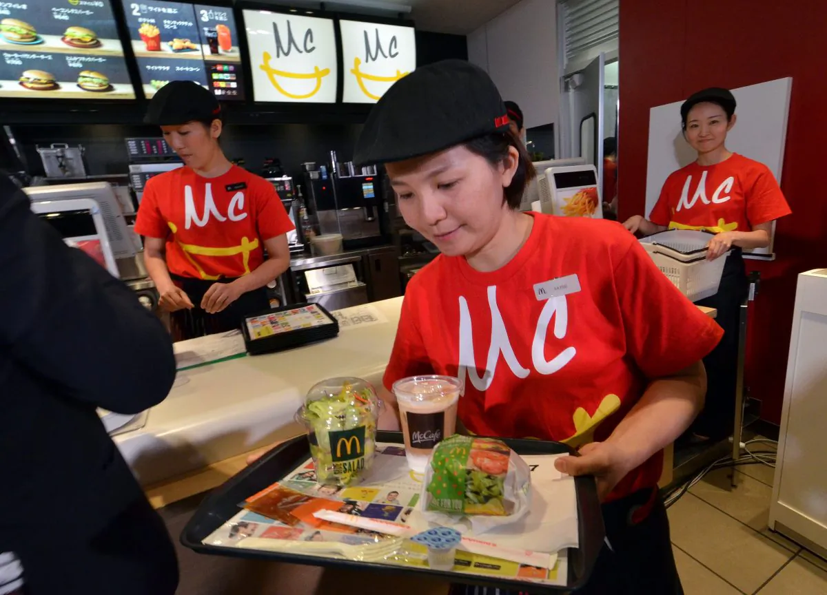 An employee of McDonald's Japan serves the new menu "Vegetable Chicken Burger" as the company president Sarah Casanova announces the new business strategy at a restaurant in Tokyo on May 21, 2015. (Yoshikazu Tsuno/AFP/Getty Images)