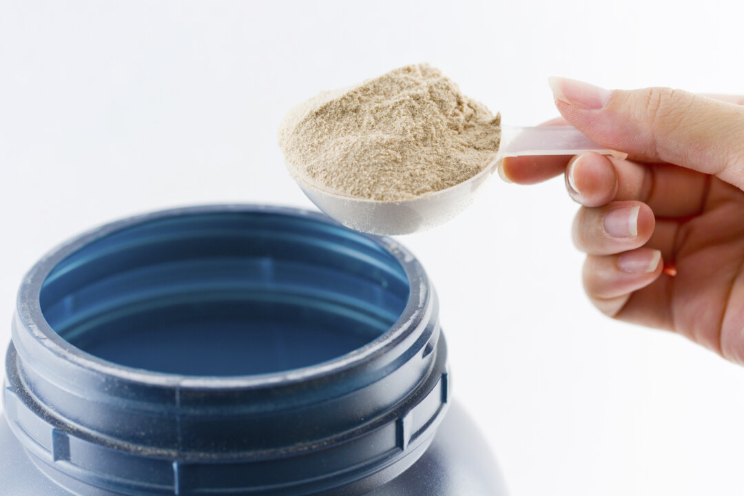 A hand weighs out protein powder. (