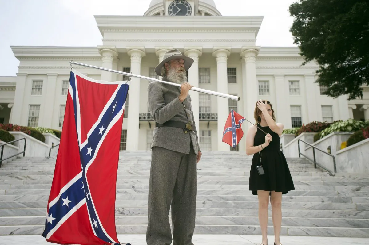 In this Saturday, June 27, 2015 file photo, Dan Williams, 65, of Ashville, Ala., holds a Confederate flag while standing with his daughter Bonnie-Blue Williams, 15, in front of the Alabama State Capitol building during a Confederate flag rally in Montgomery, Ala. ((Albert Cesare/The Montgomery Advertiser via AP)