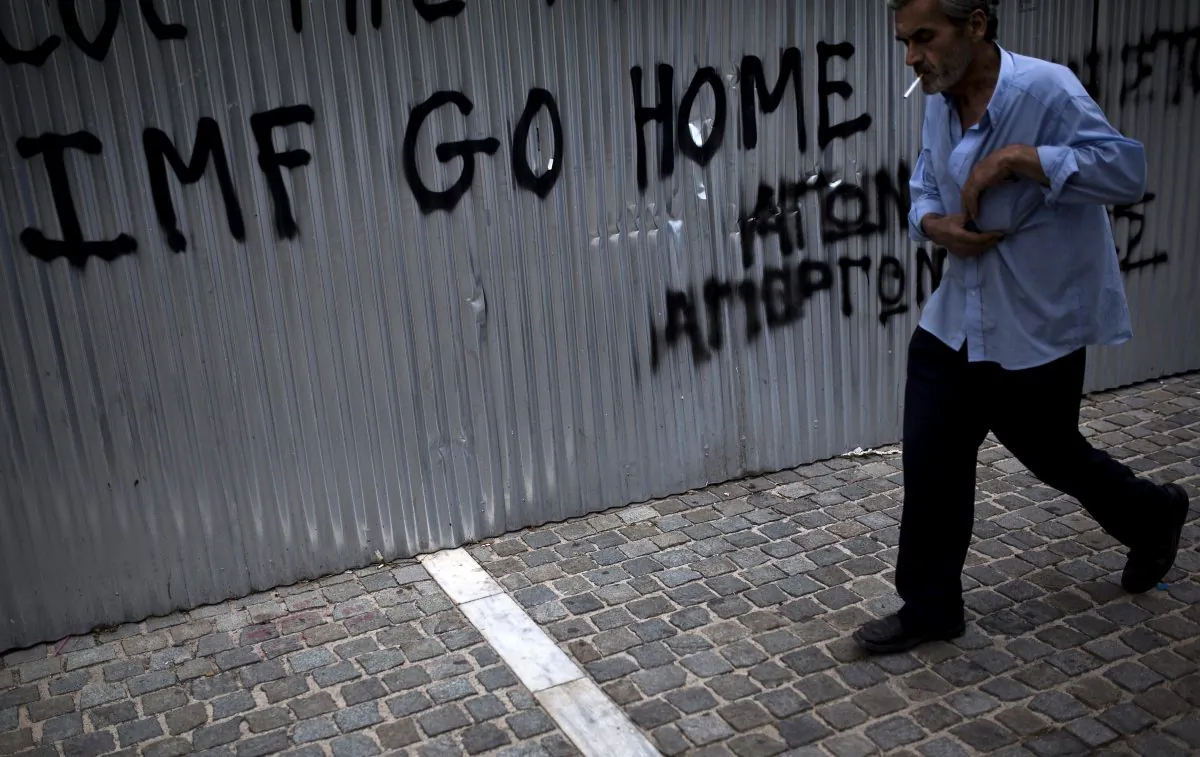 A man walks in front of a graffiti reading “IMF Go Home” in Athens, Greece, on June 27, 2015. (Angelos Tzortzinis/AFP/Getty Images)