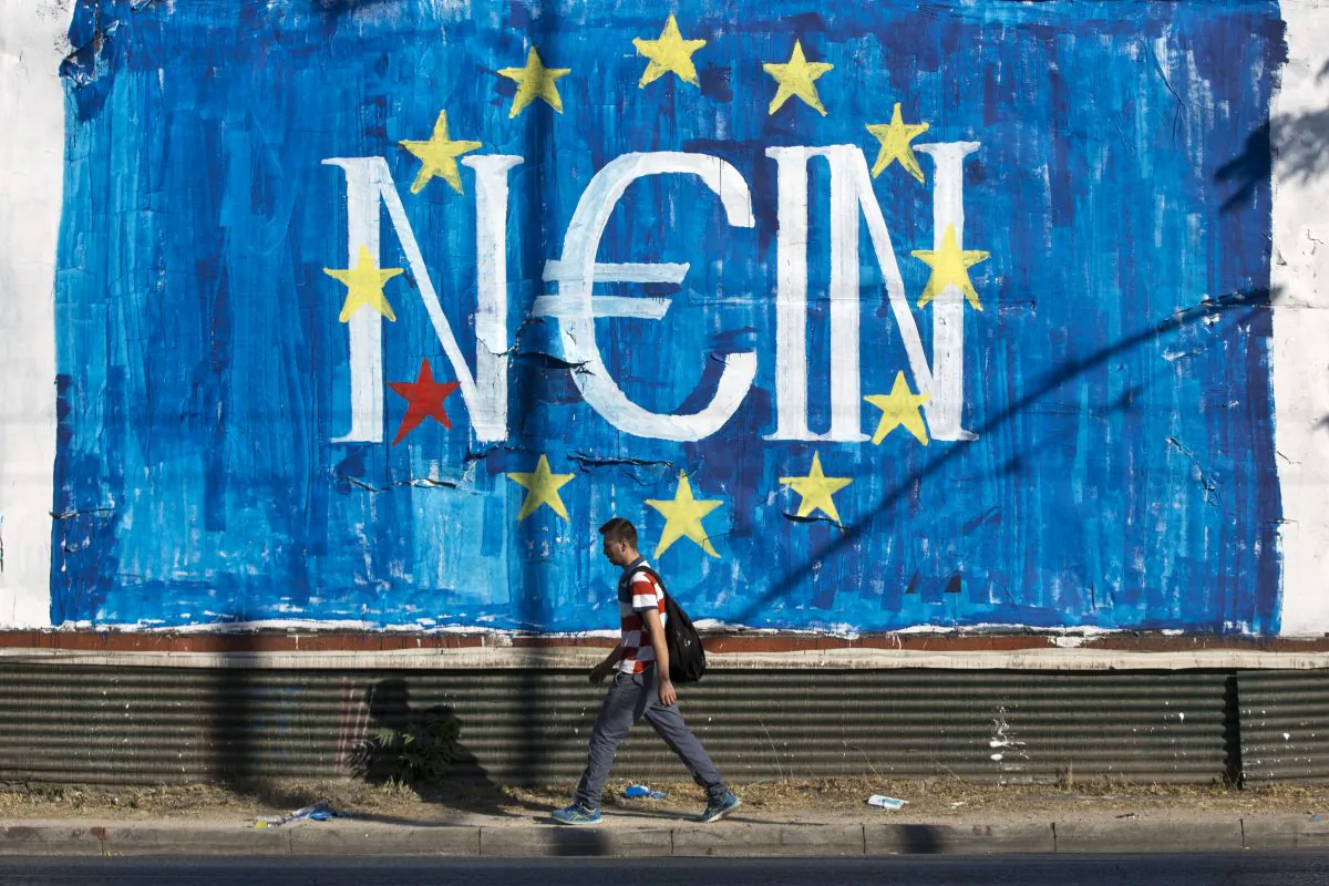 A man walks past a graffiti made by street artist N_Grams  that  read ''NO'' in German but also ''YES, IN'' in Greek language in Athens, on Sunday, June 28, 2015. (AP Photo/Petros Giannakouris)