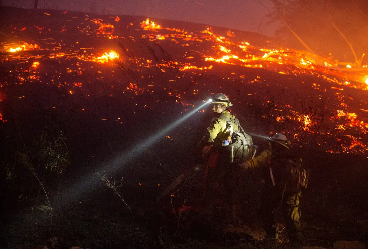 In this Sunday, June 28, 2015 photo provided by The Wenatchee World, U.S. Forest Service firefighters from Leavenworth cut brush near houses in northern Wenatchee, Wash. (Don Seabrook/The Wenatchee World via AP)