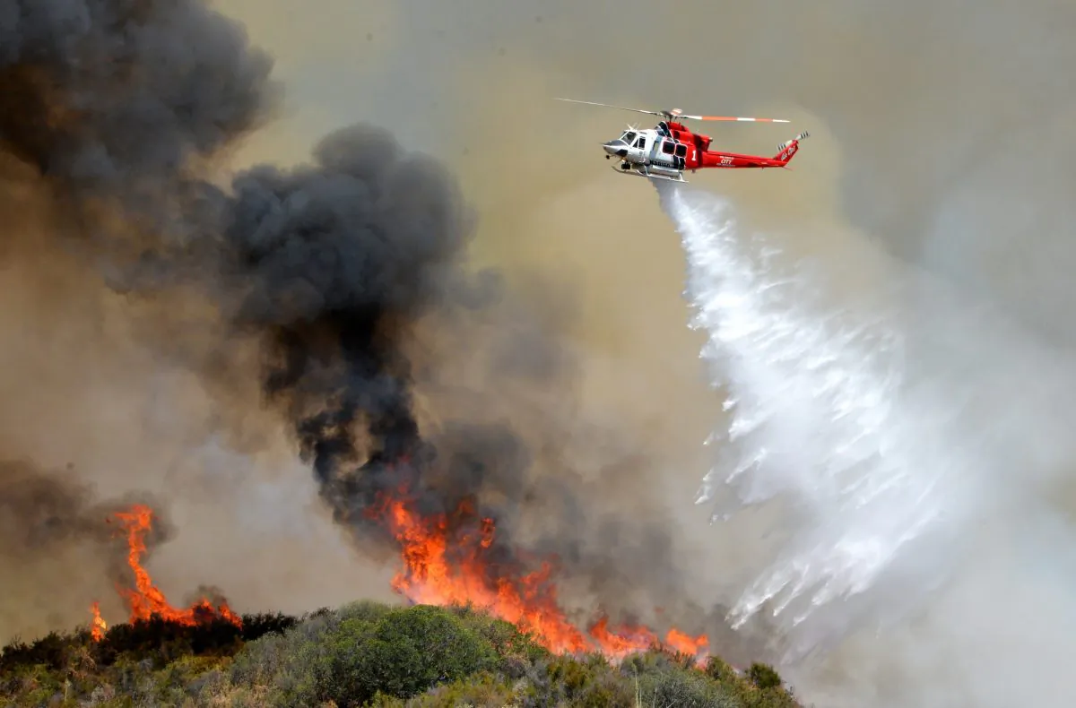A Los Angeles City Fire helicopter drops water on flames, Wednesday, June 24, 2015, in Santa Clarita, Calif. (AP Photo/Rick McClure)
