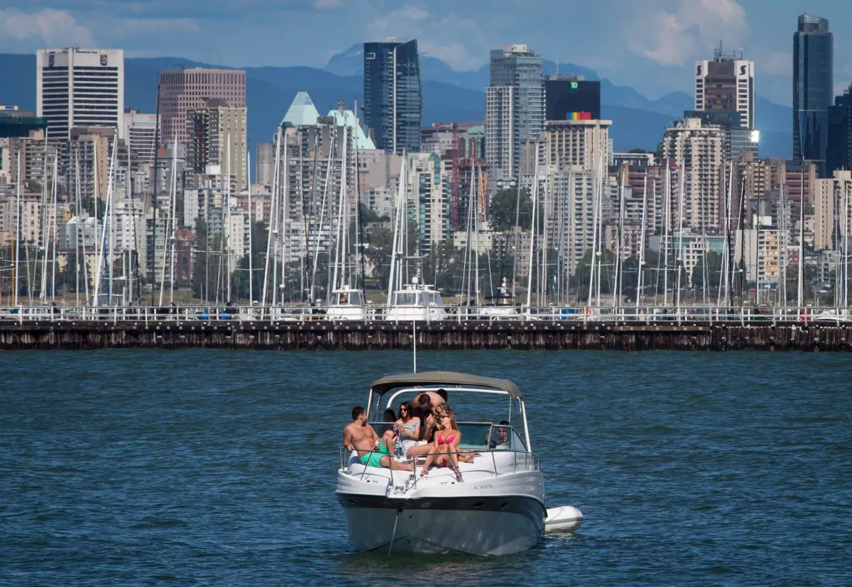 People relax on a boat off Jericho Beach in Vancouver on June 13, 2015. Nearly half of Canadians will dip into their savings or take on debt as they look to make the most of the summer weather, according to a new poll. (The Canadian Press/Darryl Dyck)