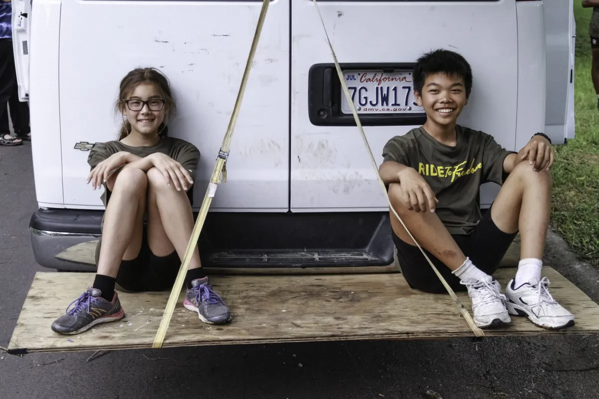 Aila Verheijke and Tanner Gao taking a break on the back of the Ride2Freedom van. (Chris Jasurek/Epoch Times)