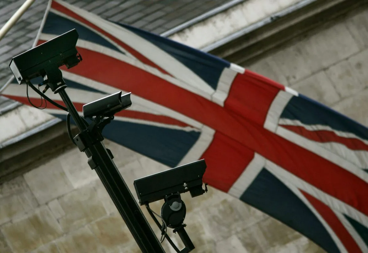 Closed-circuit surveillance cameras, with a Union flag at the rear, keep watch in central London on July 5, 2005. (Lefteris Pitarakis/AP Photo)