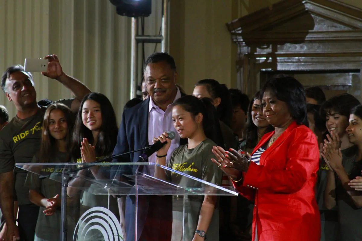 Ride2Freedom leader Annie Chen (Center) addresses the audience at Rainbow/Push headquarters while the Rev. Jesse Jackson (Left) and Rep May Flowers look on. (Chris Jasurek/Epoch Times)