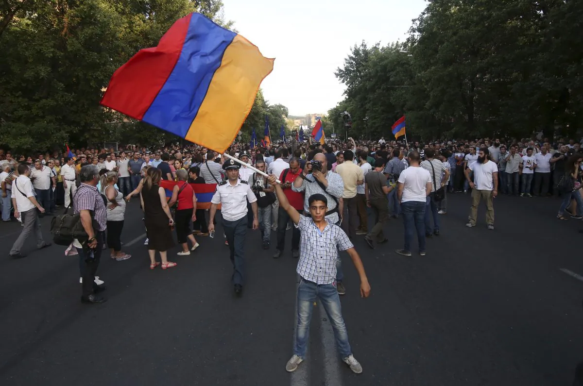 In this photo taken late Monday, June 22, 2015, an Armenian protester waves a national flag during a protest rally in the Armenian capital of Yerevan against a hike in electricity prices. (Hrant Khachatryan/PAN Photo via AP)